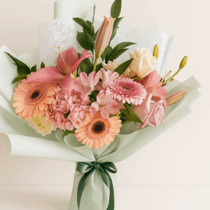 Ramo Aurora Pastel Fioretta con gerberas, lirios y rosas en tonos pastel, envuelto en papel verde menta con lazo verde. Arreglo floral elegante y femenino Fioretta.
