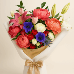 Ramo Euforia Fioretta con peonías coral, tulipanes marfil y anémonas azul violeta, envuelto en papel beige con lazo dorado. Arreglo floral vibrante y elegante Fioretta.