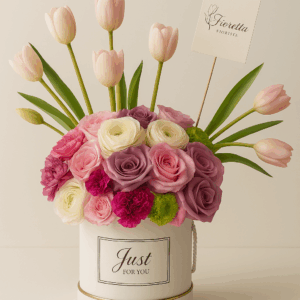 Arreglo Encanto de Primavera Fioretta con tulipanes, rosas y ranúnculos en tonos pastel dentro de una caja blanca con borde dorado. Arreglo floral elegante y moderno Fioretta.
